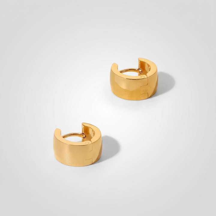 Chunky Huggie Hoops – gold-tone wide-band huggie hoops, angled view on grey studio background
