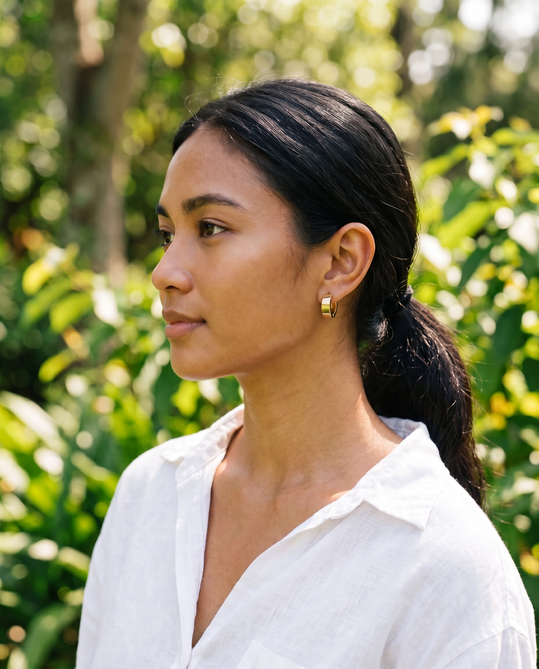 Chunky Huggie Hoops – gold-tone chunky huggie hoop worn on a model outdoors, side profile
