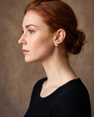 Chunky Huggie Hoops – gold-tone chunky huggie hoop worn on a model's ear, side profile