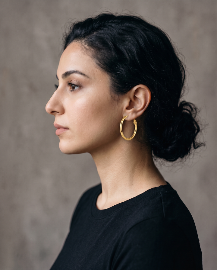 Everyday Hoops: model with dark hair wearing a thin gold-tone hoop earring, side profile