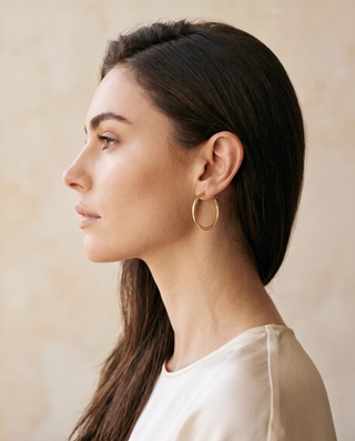 Everyday Hoops: model wearing a thin gold-tone 14 mm hoop earring, side profile