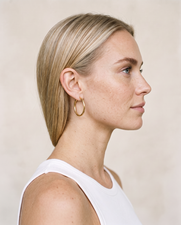 Everyday Hoops: model with sleek hair wearing a thin gold-tone hoop earring, side profile