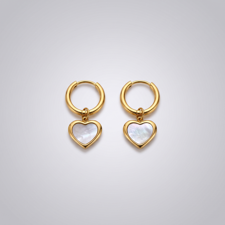 Heart Huggies - gold-tone huggie hoops with white shell heart charms, angled view