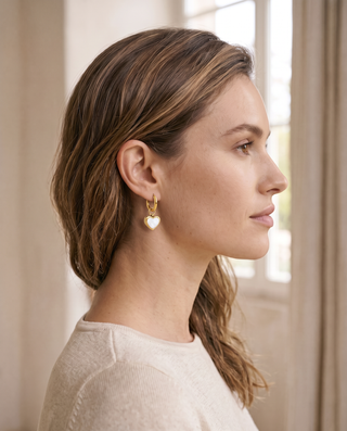 Heart Huggies worn on the ear - gold-tone huggie hoop with white shell heart hanging below the lobe
