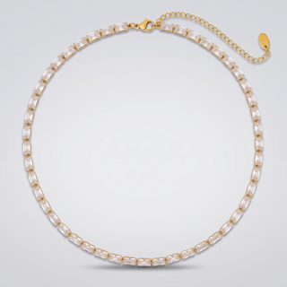 Classic Tennis Necklace in gold-tone with clear baguette zirconia stones, laid flat on a grey background