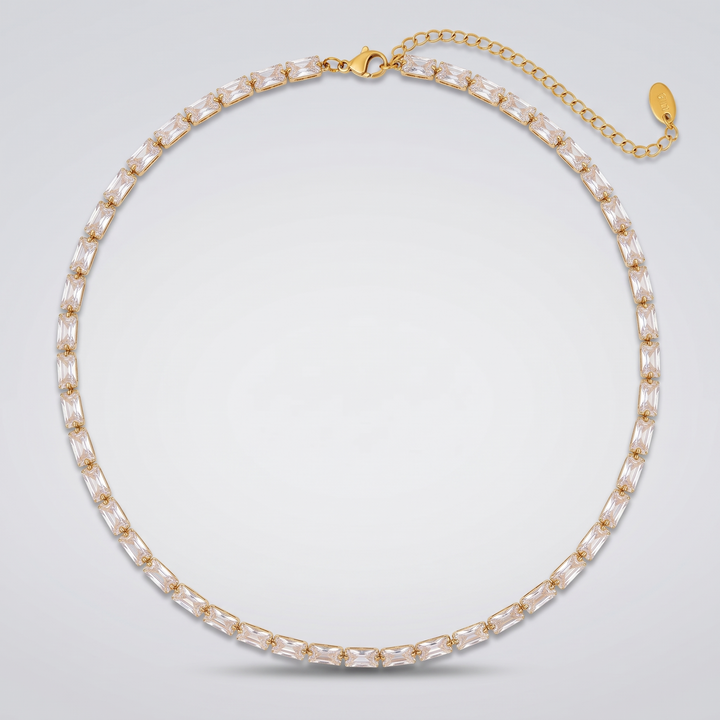 Classic Tennis Necklace in gold-tone with clear baguette zirconia stones, laid flat on a grey background