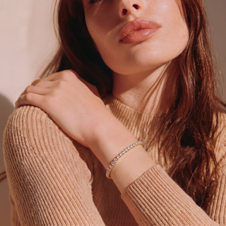 Woman in a beige knit top wearing the Petite Tennis Bracelet on her wrist, hand resting on her shoulder