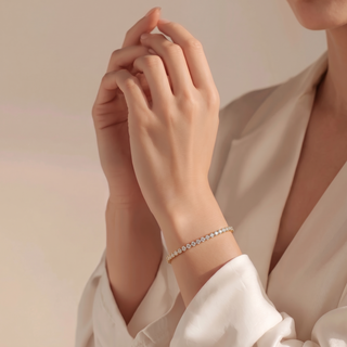 Petite Tennis Bracelet worn on the wrist, hands raised in front of a cream blouse