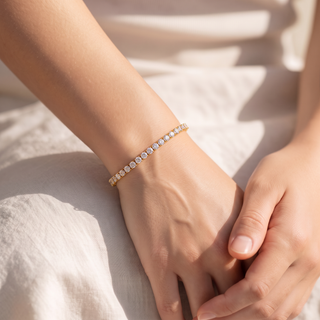 Petite Tennis Bracelet worn on the wrist, hands resting in the lap on white linen