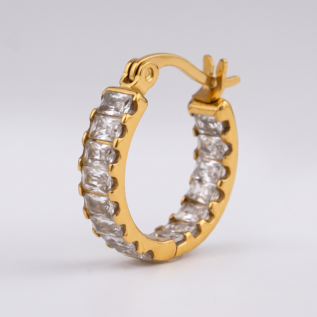 Close-up of the clear baguette-cut zirconia stones and hinge of the Tennis Huggie Hoop