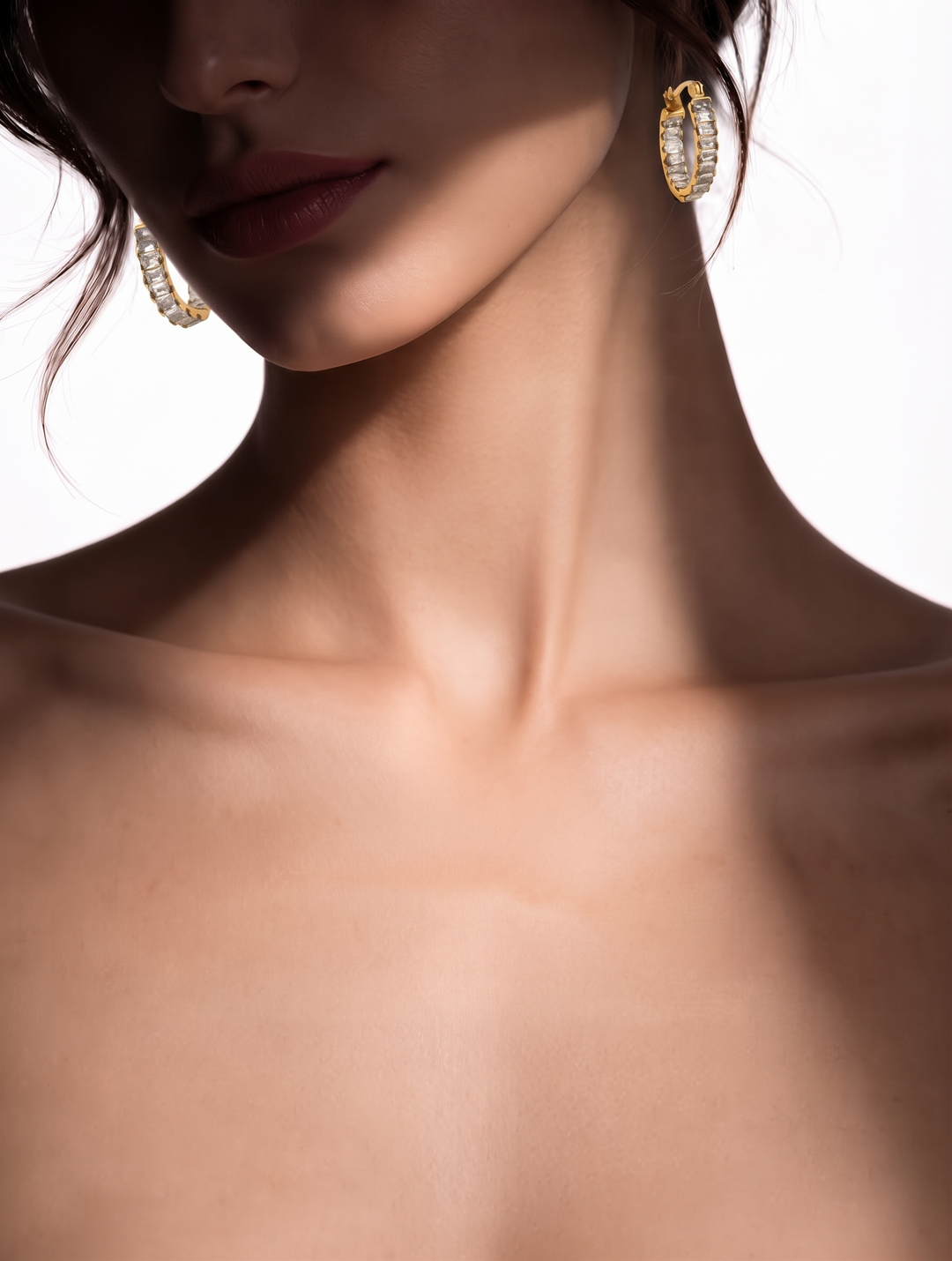 Model with bare shoulders wearing the gold-tone Tennis Huggie Hoops on both ears