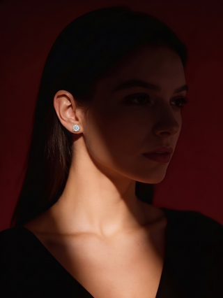 Model wearing a Classic Solitaire Stud in silver-tone against a dark red background