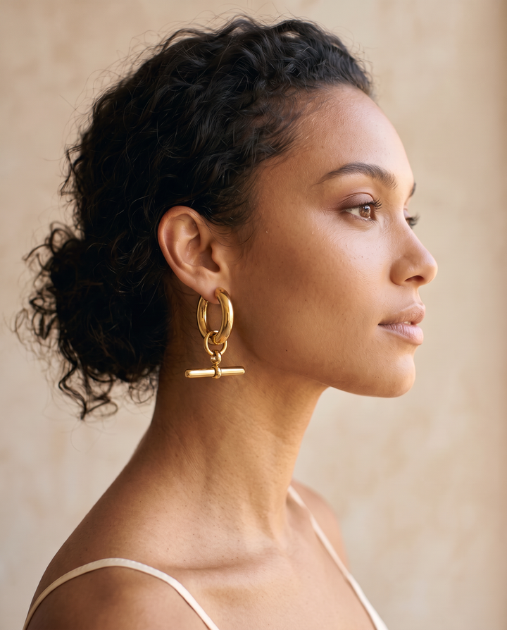 Model with curly hair wearing a gold-tone T-Bar Hoop earring, side profile